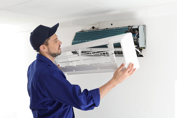 Male-technician-repairing-air-conditioner-indoors